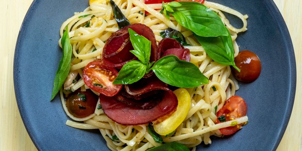 Bowl of pasta with bresaola tomato basil feta